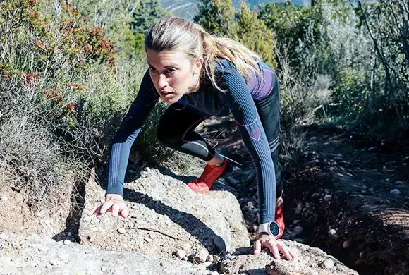 iv-therapy-endurance Female athlete climbing a rugged terrain during an outdoor endurance challenge.