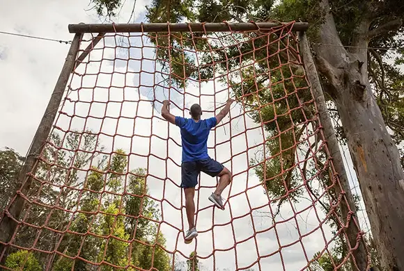 iv-therapy-obstacle-race Athlete climbing a net obstacle during a race, demonstrating agility and strength.